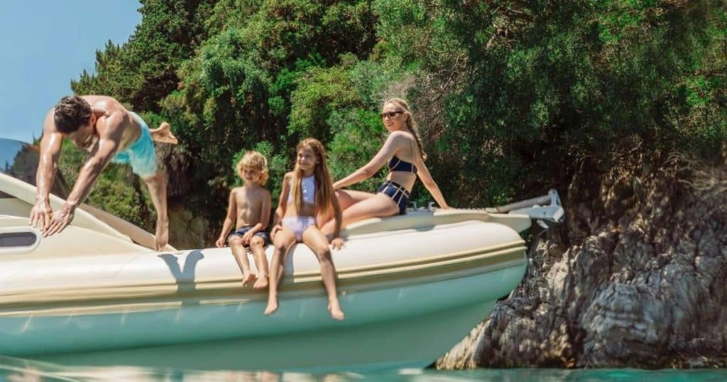 Family enjoying a private boat experience at Ikos Olivia all-inclusive resort in Halkidiki, Greece, with parents and young children relaxing by calm Mediterranean waters