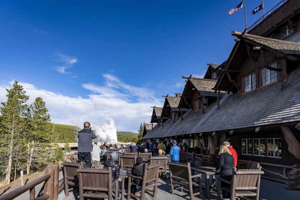 Guests on the balcony of Old Faithful Inn photographing the geyser at Yellowstone National Park