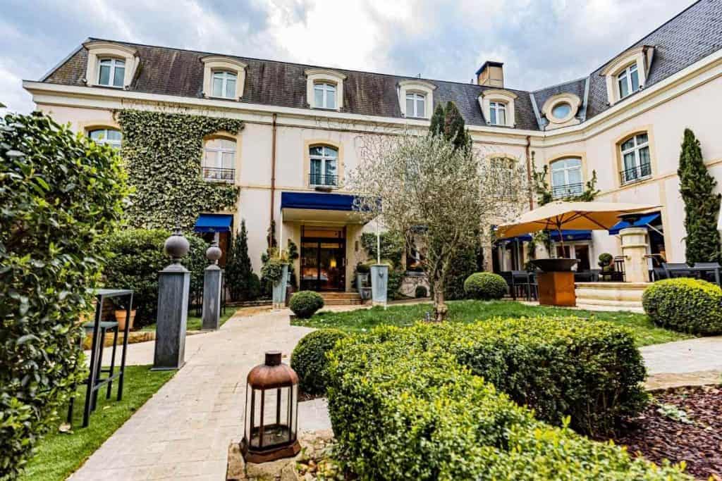 Lush courtyard at Cèdre Beaune Hotel with manicured garden and classic French architecture