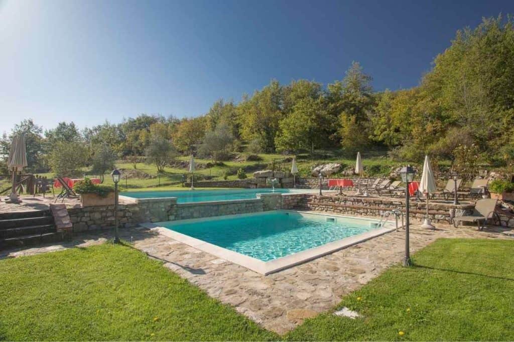 Private outdoor pools at CHIANTIGAIO villa in Tuscany surrounded by sun loungers and countryside