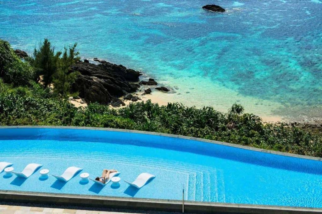 Outdoor pool at Halekulani Okinawa overlooking a serene beach and turquoise waters