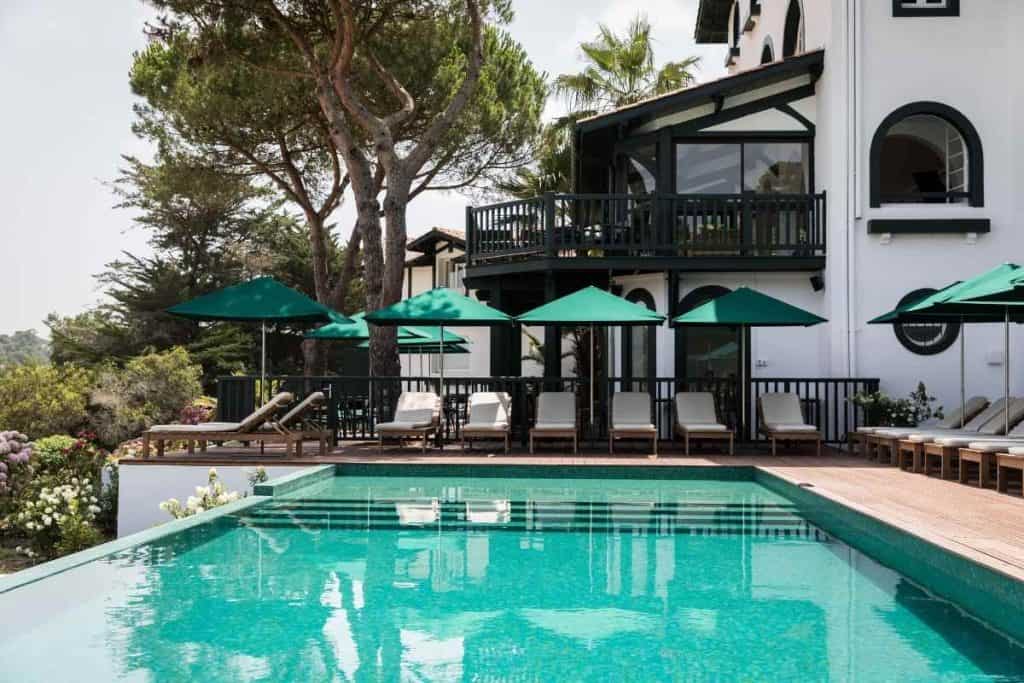 Peaceful pool area at Les Hortensias du Lac with lounge chairs and lush greenery