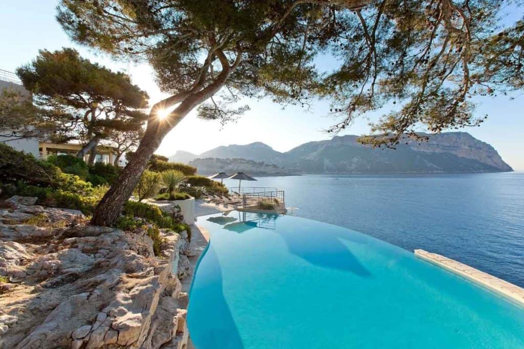 Infinity pool at Hôtel Les Roches Blanches with sea and mountain views surrounded by greenery